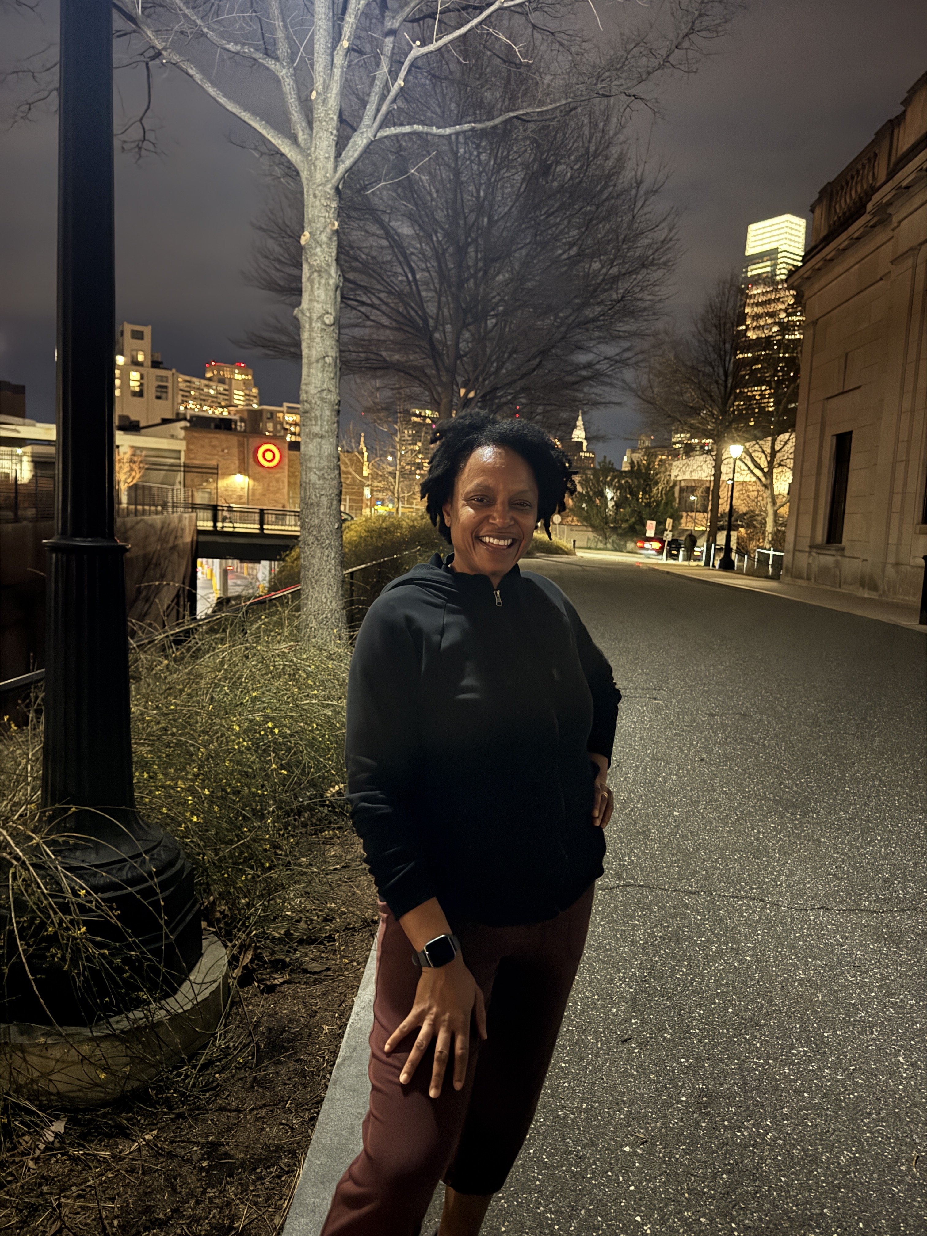 Runner smiling on a night run in Philadelphia with city lights in the background